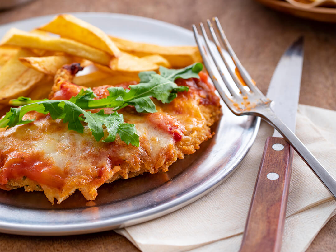 Milanesitas de pollo a la napolitana con salsa portuguesa y rúcula