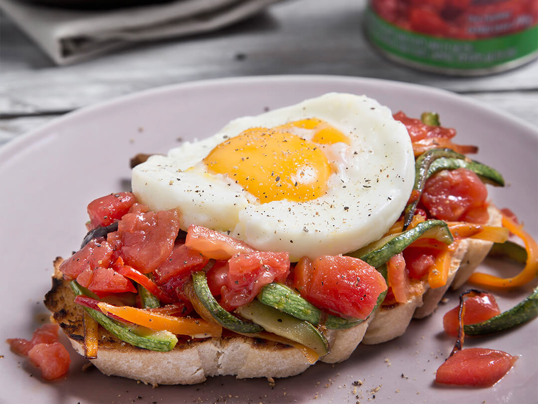 Bruschetta de vegetales salteados, con tomate cubeteado y huevo frito