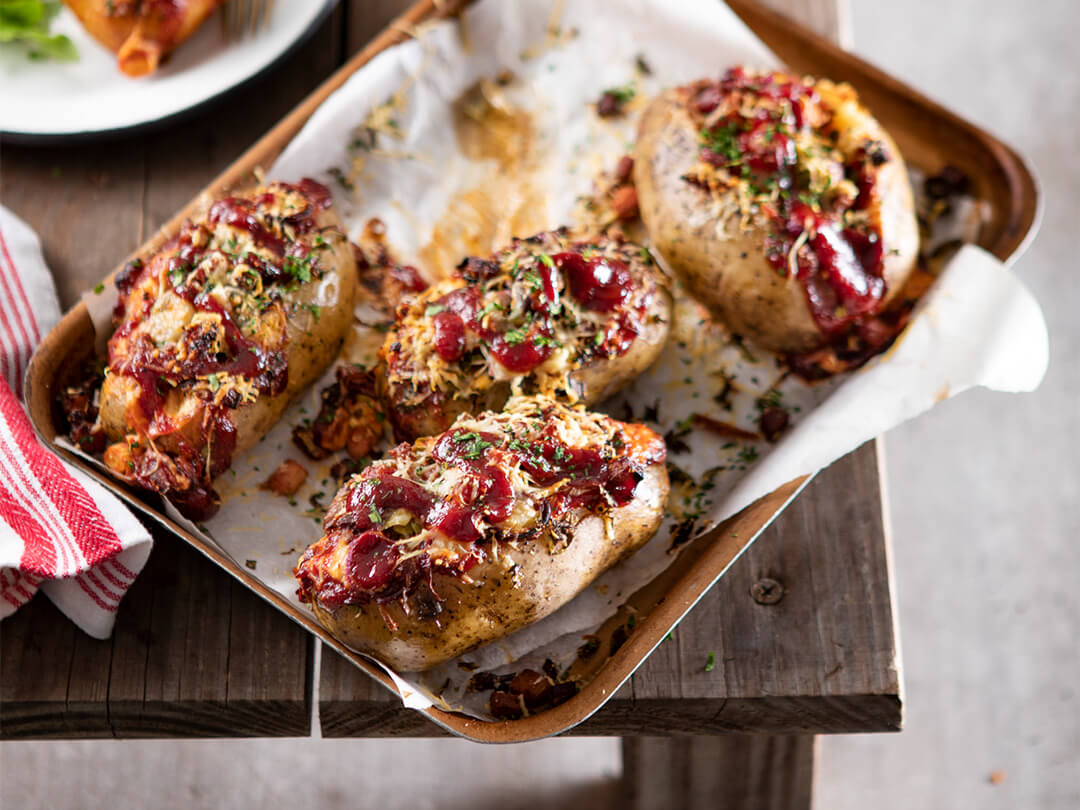 Papas asadas rellenas con cebolla de verdeo, queso crema, panceta crocante y kétchup