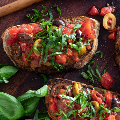 Bruschetta de tomate cubeteado con cubierta de aceitunas, hojas de albahaca y aceite de oliva