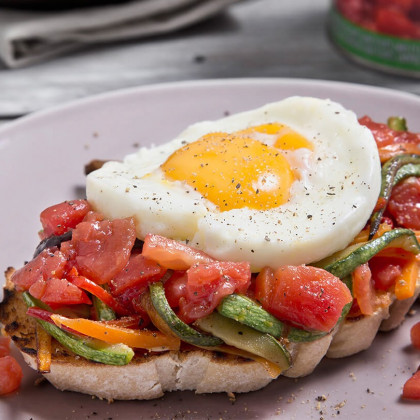 Bruschetta de vegetales salteados, con tomate cubeteado y huevo frito